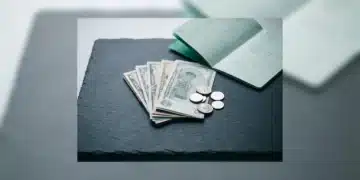 Unlocking Financial Acumen: Expert Perspectives on Personal Wealth Management A person's hands meticulously organizing banknotes and silver coins on a slate surface next to a green financial ledger, symbolizing intentional budgeting and personalized wealth management.